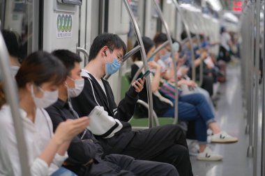 Coronavirus COVID-19 enfeksiyonunu önlemek için Şangay 'daki metro treninde oturan cerrahi maske takan birçok yolcu...