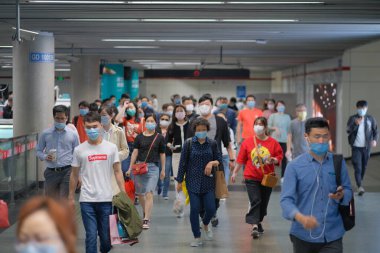 Coronavirus COVID-19 enfeksiyonunu önlemek için, Çin 'de yoğun saatlerde metro istasyonunda ameliyat maskesi takan banliyö çalışanları