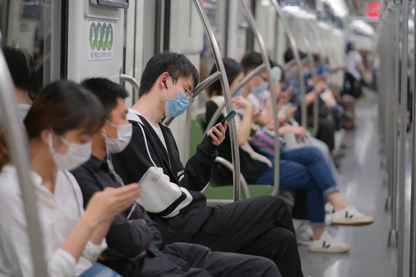 Coronavirus COVID-19 enfeksiyonunu önlemek için Şangay 'daki metro treninde oturan cerrahi maske takan birçok yolcu...