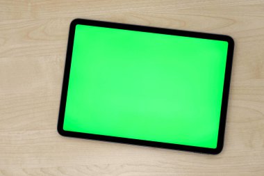 Kalıplı ahşap masadaki yeşil ekran tablet aygıtının üst görünümü