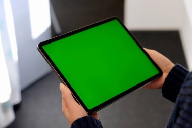 Yeşil ekran tablet bilgisayar tutan insanların omzunun üstünden. Bulanık arkaplan