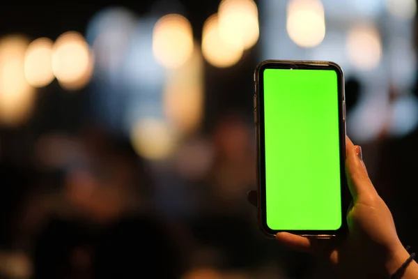 Yeşil ekran akıllı telefonu göstererek bir elinizi kapatın. Bulanık bokeh arkaplanı