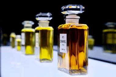 Beyaz parlak tahta üzerinde ünlü 5 numaralı Chanel parfüm şişelerini kapat. Beş numaralı Chanel parfüm koleksiyonunun perspektif görüntüsü. Chanel Paris 'in sergisinde.