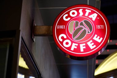 Şangay / Çin-Temmuz 2019: Parlak Costa kahve kutuları geceleri saçakların altında kahve dükkanının önünde asılı duruyor. Bulanık arkaplan. Dünyaca ünlü kahve markası.