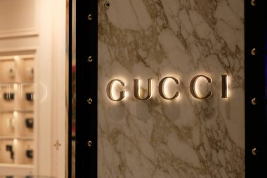 Shanghai / China-July 2019: Parlak GUCCI logosunu geceleri mağazanın dışındaki granit duvara kapatın. Mağazadaki odaklı olmayan ürünler. Ünlü İtalyan lüks moda ve deri ürünleri markası..
