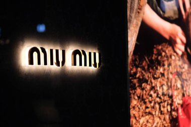 Miu Miu 'nun logosunu koyu arka planda kapat. Geceleri mağazanın dışındaki odaksız reklam lambası.. 