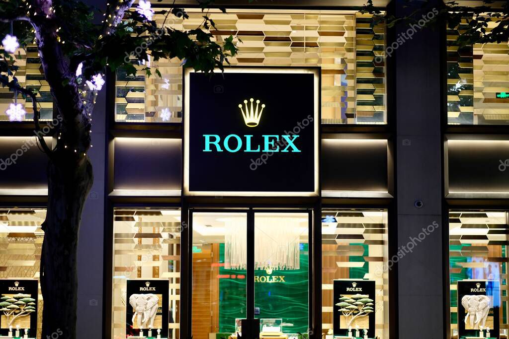 Shanghai/China-July 2019: front view of ROLEX store in Shanghai at night. Golden illuminated windows with shining brand logo in the center. A Swiss luxury watch manufacturer and popular in China.