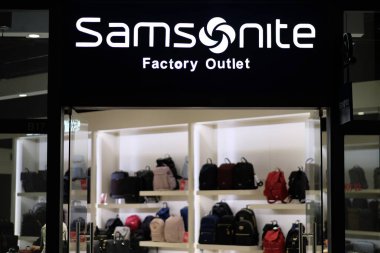 Şangay / Çin-Ekim 2019: Florentia Village Outlets 'teki Samsonite Fabrikası' nın cephesi. Beyaz markalı logo. İçerideki aydınlanmış giyim mağazası. Amerikalı bir bagaj üreticisi ve perakendecisi.