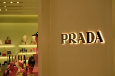 Geceleri PRADA 'nın logosunu mağazanın dış duvarına kapatın. İtalyan lüks moda markası. Görüntü penceresi arkaplanı.