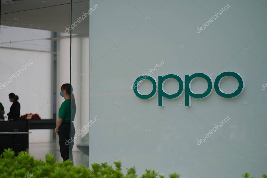 Close up OPPO shop sign on exterior wall of store. Blur shop staff and customer inside. Chinese electronic brand