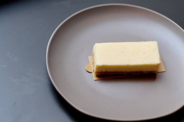 Kahverengi kremalı pastayı kırmızı-kahverengi tabağa koy. Gri tablo arkaplanı