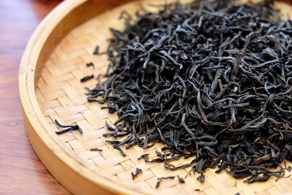 Sarı bambu tabaktaki kuru çay yapraklarını kapatın. Bulanık arkaplan. Geleneksel Çin çay kültürü