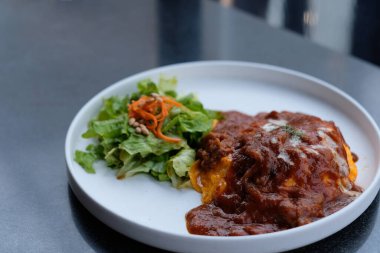 Omlet pilavı (omurice) ve sebzeli omleti beyaz tabakta masaya koy. Bulanık arkaplan.