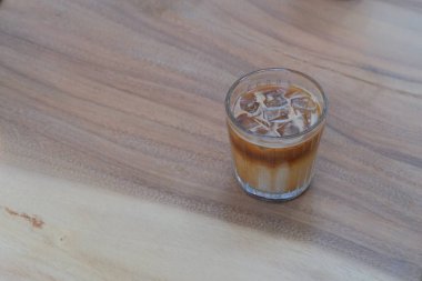 Bir bardak buzlu kahveyi desenli ahşap masaya koy. Bulanık arkaplan