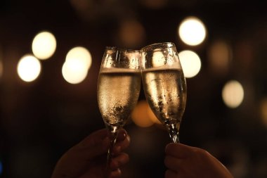 İki elinle bardağı tut, karanlıkta şerefe. Altın bokeh arkaplanı