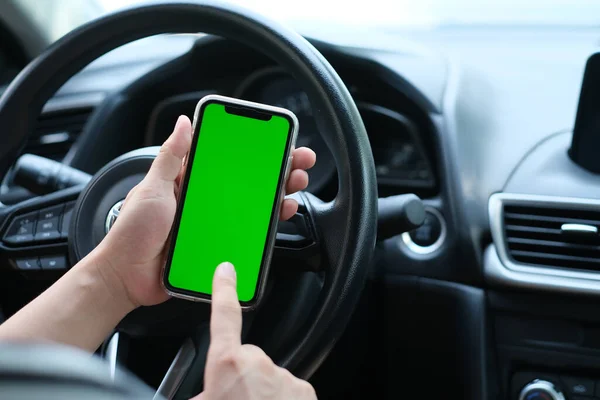 Arabadaki yeşil ekran akıllı telefonu dinleyen bir adamın omzundan. Bulanık arkaplan