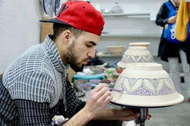 Fez / Fas-Mart 2018: Yakışıklı genç adam çömlek çömleği çiziyor. Görüntü atölyesi ve turist geçmişi. Fez 'de seramik geleneksel endüstridir..