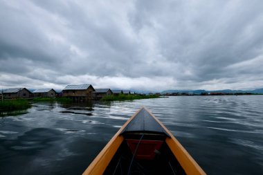 Shan State Myanmar 'daki Inle Gölü' nde tekne gezisinin birinci şahıs görüntüsü. Suyun üstündeki evler. Bulutlu gökyüzü. Bakış açısı