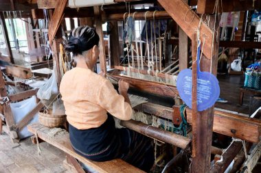Shan State / Myanmar-Sep.2019: Tahta tezgahta oturan bir kadın Birmanyalı. Eşarp ve longyi yapmak için pamuklu ve ipekli nilüfer kökü kullandım. Inle Gölü 'nde geleneksel endüstri. Dünyada eşi benzeri yok.
