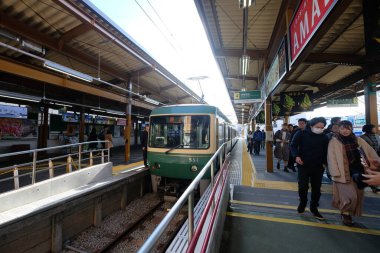 Kamakura, Kanagawa / Japonya-Aralık 2019: Tren Kamakura istasyonuna ulaşır. Enoshima Elektrik Demiryolu Terminal İstasyonu. Platformda yürüyen turistler