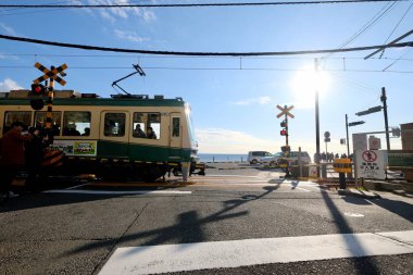 Kamakura, Kanagawa / Japonya-Aralık 2019: Enoshima Electric Railway treni Kamakurakomae İstasyonu yakınlarından geçiyor. Güneşli mavi gökyüzünün altında. Çizgi filmdeki ünlü sahne Slam Sunk