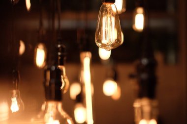 Karanlık ortamda altın renkli ampullere yakın. Retro ışıkların bulanık arkaplanı