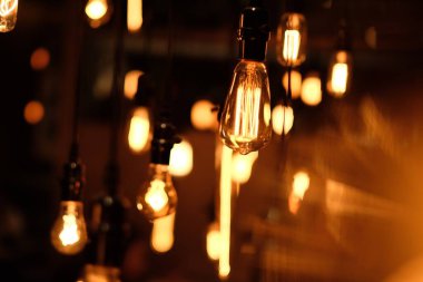 Karanlık ortamda altın renkli ampullere yakın. Retro ışıkların bulanık arkaplanı