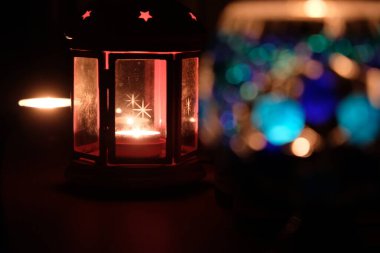 Geceleri renkli mum ışıklarını kapat. Şeffaf fenerde mum. karanlık ortam