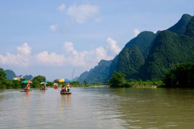 Yangshuo Guilin Çin 'de huzurlu nehirde birkaç bambu salları var. Perspektif yeşil dağlar. Beyaz bulutlu mavi gökyüzü. Karst toprak formu