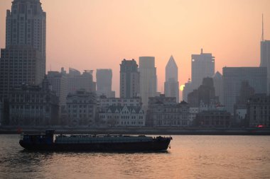 sunset of The Bund of Shanghai by the side of Huangpu River. Cargo ship on water clipart