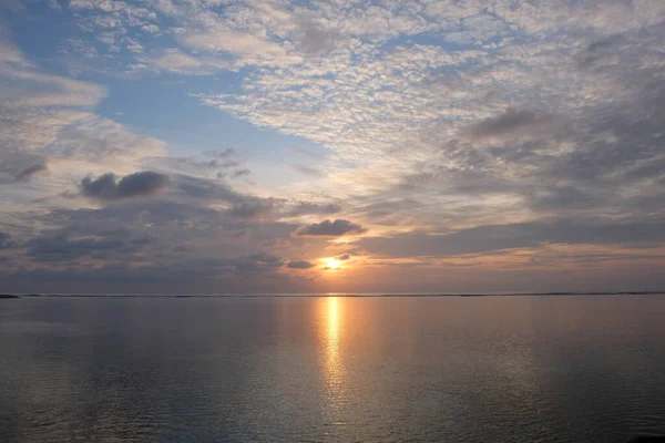 burning sun rising above sea horizon. white cloudy blue sky. bright yellow sunlight reflection on ocean surface. peaceful in Maldives. wide angle