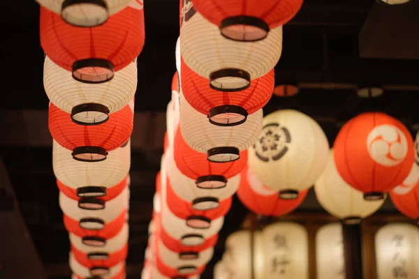 traditional Japanese red and white lanterns hanging on dark ceiling. Perspective and blur background