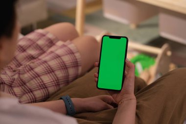 Evde elinde yeşil ekran telefon tutan kadınların omuz manzarası