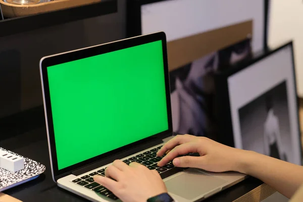 over shoulder view of hand typing on green screen laptop computer at home