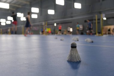 Bir badmintonu kapalı stadyum zeminine kapatın. Badminton oynayan odaksız insanlar
