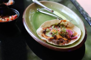 Masada tabak olan taco 'yu kapat. Geleneksel Meksika yemekleri. Bulanık arkaplan