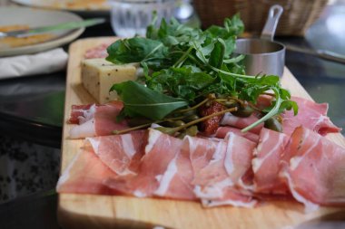 Roka yakın, ahşap tabakta pişmiş et ve peynir. Geleneksel İtalyan yemekleri. Odaklanmamış arkaplan