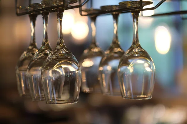 Barda baş aşağı asılı duran içki bardaklarını kapatın. Bokeh arkaplanı