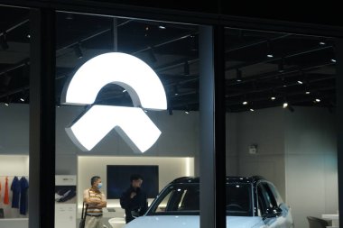 Shanghai / China-2020: NIO marka logoyu gece kapatın. NIO, Çinli elektrikli araba markası. İçerideki müşteriler elektrikli araba seçiyor