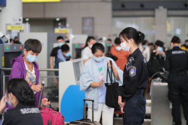 Şangay / Çin-Ekim 2020: Koronavirüsü önlemek için Şangay Hongqiao Tren İstasyonu 'nda yüz maskesi takan güvenlik görevlisi ve yolcular. Çin Ulusal Günü 'nde demiryolu yolcu servisiyle meşgul.