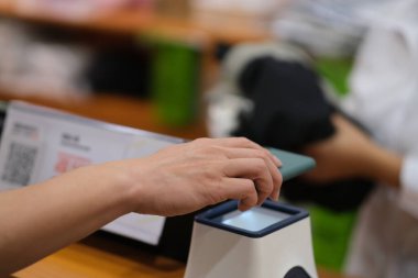 Giysi dükkanında ödeme yapmak için cep telefonunu kapat. yumuşak odak