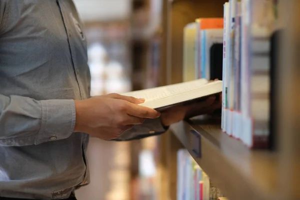 Täta Händer Hålla Bok Nära Bokhylla Biblioteket Suddig Bakgrund — Stockfoto