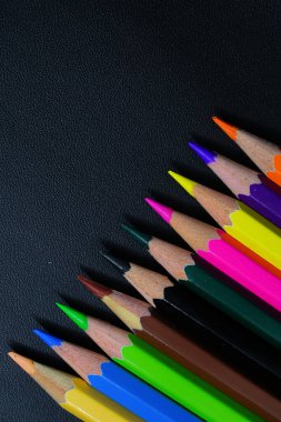 Siyah arkaplan üzerinde çok renkli kalemler ve metin için boş alan 
