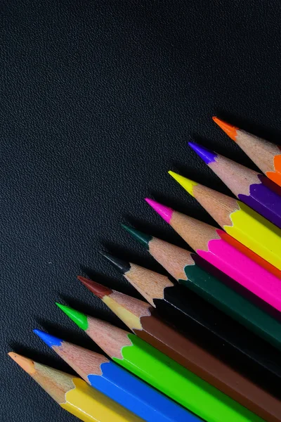 Siyah arkaplan üzerinde çok renkli kalemler ve metin için boş alan 