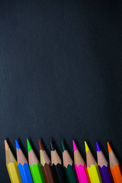Siyah arkaplan üzerinde çok renkli kalemler ve metin için boş alan