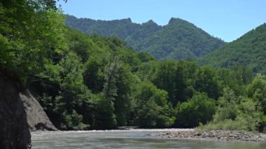 Nehrin üzerinde dağ manzaralı uçan kamera.