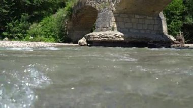    Nehir köprünün altından akar.