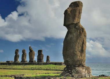 Okyanus yakınında bulutlu gökyüzüne karşı Moai heykelleri, Paskalya Adası, Şili (Rapa Nui)
