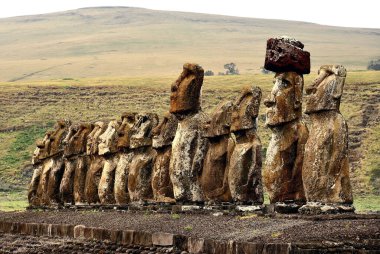 Ahu Tongariki 'nin Moai heykelleri açık gökyüzüne ve yeşil yüksek tepeye karşı. Paskalya Adası, Şili (Rapa Nui)