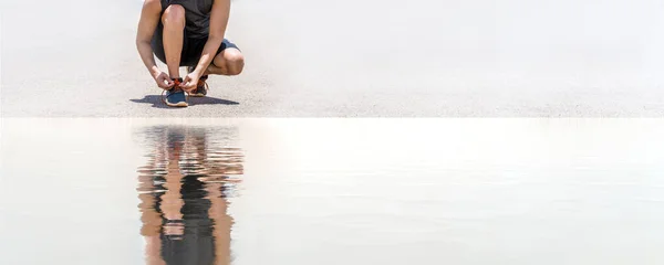 Erkek koşusu spor ayakkabıları bağlar. Beton yolda koşuya hazır olun.